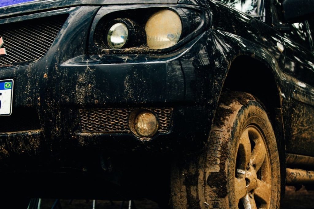 Front end of a mud-covered pickup with its factory bumper